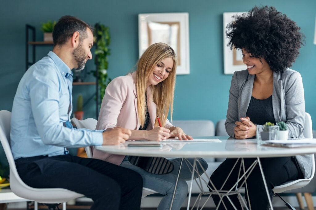 Happy young couple signing bank loan agreement with real-estate agent to buying a house